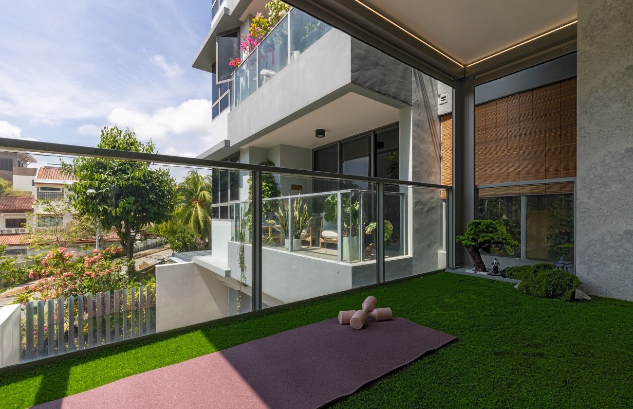 The balcony of the apartment with a yoga mat, dumbbells, and a bonsai plant
