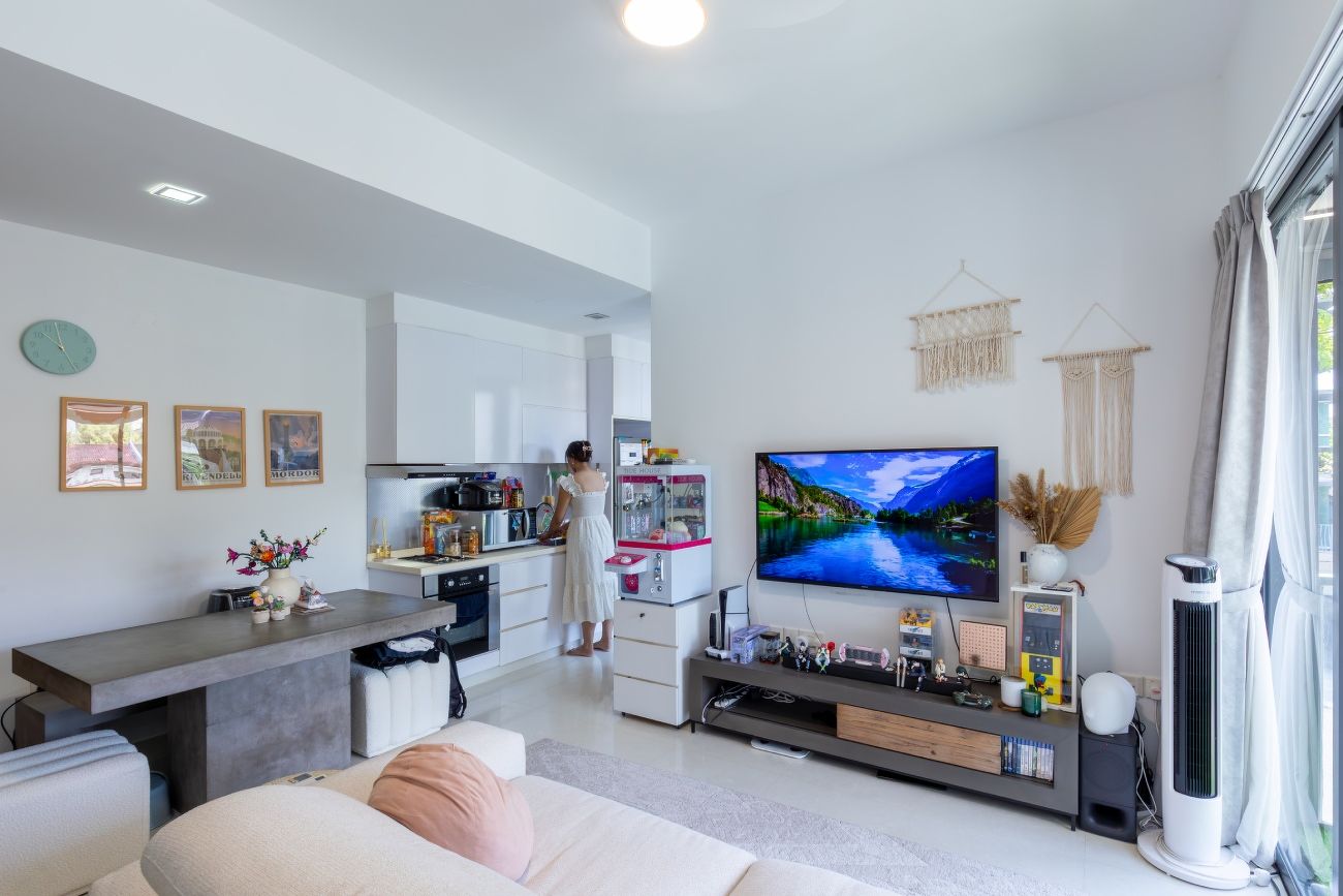 The living area and kitchen of the apartment, with a sofa, dining table, TV console, and a functioning claw machine